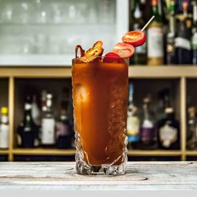 A caesar cocktail with a decked out garnish with cherry tomatos and bacon.