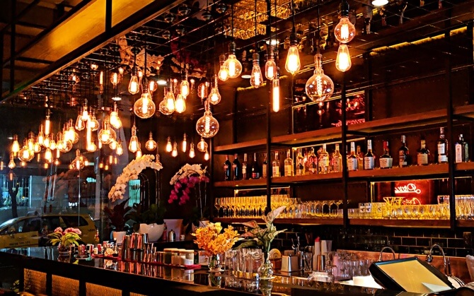 Fully stocked bar with many hanging edison bulb lights.