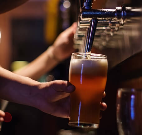 Bartender pouring a pint of beer from the tap.