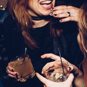 Two people with drinks in their hands laughing and haveing a good time.